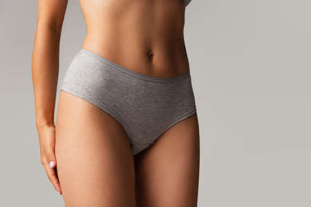 Beautiful body of young caucasian woman in grey lingerie isolated on gray studio background. Natural...