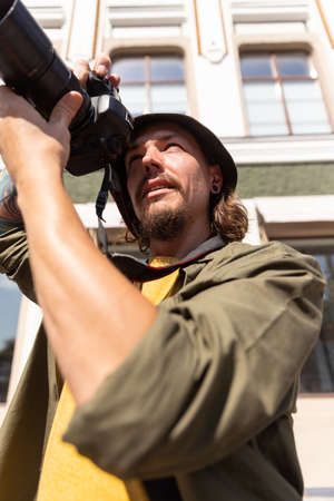 Portrait of young man, photographer, cameraman with professional camera, equipment during working summer day outdoors. Concept of occupation, job, educationの写真素材
