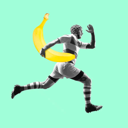 Fit young man running with good food on color background. Male rugby player with banana as ball. Healthy eating concept.の写真素材