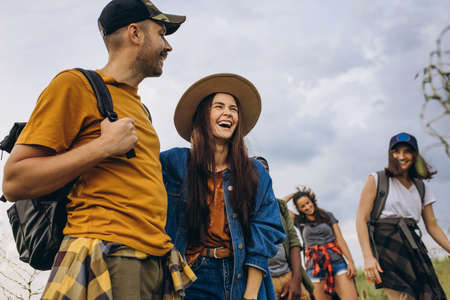Group of friends, young men and women walking, strolling together in summer forest, meadow. Active lifestyle, friendship, care, ecology conceptの写真素材