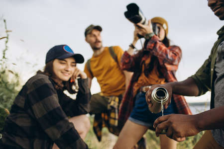 Group of friends, young men and women walking, strolling together outskirts of city, in summer...