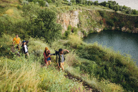 beautiful scenery. Group of friends, young men and women walking, strolling together outskirts of city, in summer forest, meadow. Active lifestyle, friendship, care, ecology conceptの写真素材