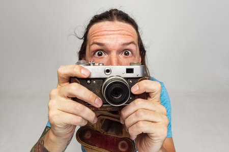 High angle view of young man, photographer, cameraman with retro camera isolated on gray studio...