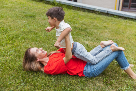 Happy mother and little cute son strolling at street, public park in summer time, outdoors. Family time, togehterness, parenting and happy childhood concept.の写真素材