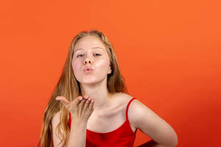 Portrait of young beautiful girl isolated on red studio background. Concept of human emotions, facial expression, youth, sales, ad.の写真素材
