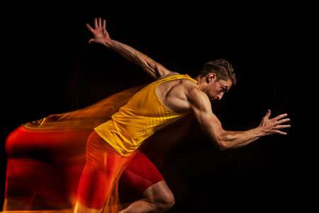 Portrait of young man, professional male athlete, runner in motion and action isolated on dark background. Stroboscope effect.の写真素材