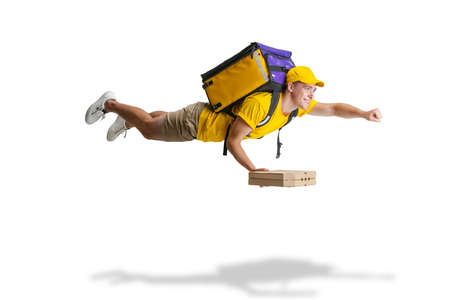 Young delivery man in yellow uniform flying to deliver order isolated on white background. Concept of convenience, speed, comfort, safety, service.の写真素材