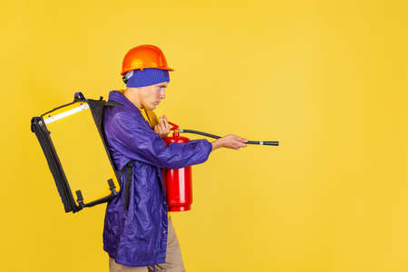 Comic portrait of young man, delivery guy in uniform isolated on yellow studio background. Concept of humor, safety, service. Complementary colorsの写真素材