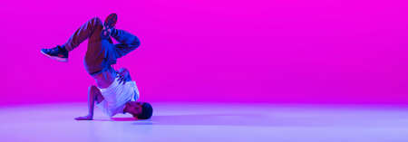 Flyer with dancing man, break dancer in action, motion in modern clothes isolated over bright magenta background at dance hall in neon light.の写真素材