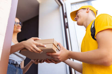 Close-up hands of deliveryman delivers order to clients, customers, buyers. Work, career, different professions concept. Idea of convenience, speed, comfort, safety, service.の写真素材