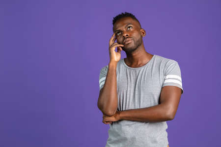 One African-american young man isolated on purple color studio background. Concept of human emotions, facial expression, youth, feelings, ad.の写真素材