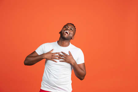 Happy African young man in casual clothes isolated on red color studio background. Concept of human...