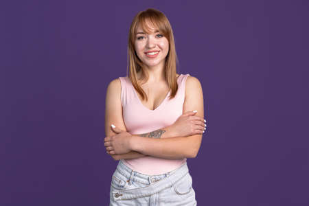 Half-length portrait of young beautiful girl isolated on purple studio background. Concept of human emotions, facial expression, youth, sales, ad.の写真素材