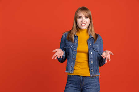 Portrait of young beautiful girl isolated on red studio background. Concept of human emotions,...