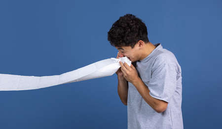 Portrait of young curly man has cold isolated over blue studio background with copyspace for ad. Concept of human emotions, fashion, beauty, youthの写真素材