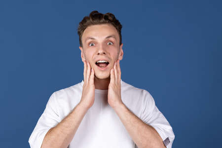 Close-up Caucasian young man with open mouth isolated on navy blue color studio background. Concept of human emotion, facial expressions, youth, feelings, ad.の写真素材
