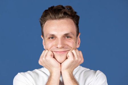 Close-up Caucasian young sweet man looking at camera isolated on navy blue color studio background. Concept of human emotion, facial expressions, youth, feelings, ad.の写真素材