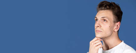 Flyer with Caucasian young man isolated on navy blue color studio background. Concept of human...