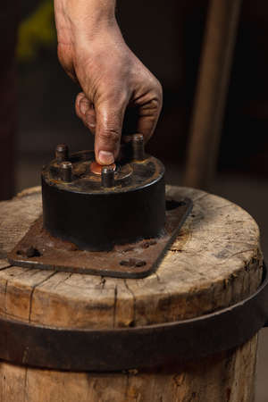 Close-up working powerful hands of male blacksmith forge an iron product in a blacksmith. Hammer, red hot metal and anvil. Concept of labor, retro professionsの写真素材