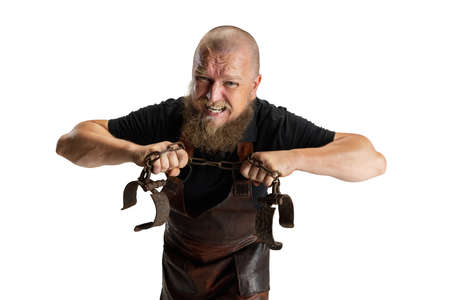 Close-up muscular bearded bald man, blacksmith wearing leather apron or uniform isolated on white studio background. Concept of labor, retro professions, power, beauty, humorの写真素材