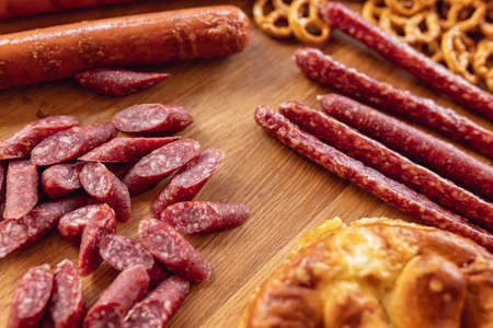 Close-up beer snacks, smoked sausages and pretzels on wooden tray. Top view. Oktoberfest holiday cuisine. Traditions, fun, joy, food and drinks.の写真素材