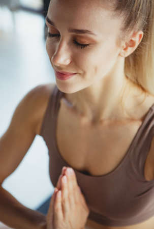 Cropped image of young slim sportive woman in sportswear doing yoga exercise on sports mat at yoga...