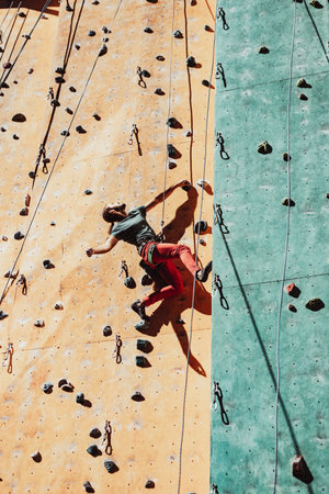 One Caucasian man professional rock climber workouts on climbing wall at training center in sunny day, outdoors. Concept of healthy lifestyle, power, strength, motion.の写真素材