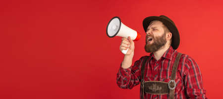 Comic portrait of bearded man, waiter in hat and traditional Bavarian costume shouting at megaphone...