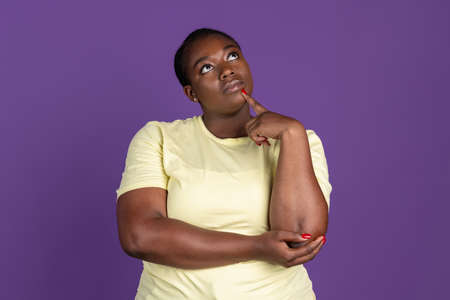 Half-length portrait of African pretty woman isolated on purple, lilac color studio background....