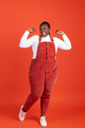 Bright portrait of African happy woman isolated on red studio background. Concept of human emotions,...