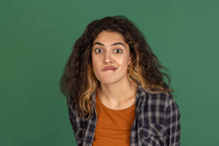 Making faces. Portrait of Latino beautiful girl isolated on green, vintage color studio background. Concept of human emotionsの写真素材