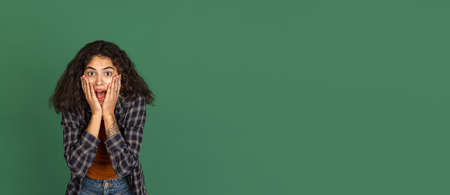 Flyer. Portrait of Latino beautiful girl isolated on green, vintage color studio background. Concept of human emotions, facial expression, natural beauty, diversityの写真素材