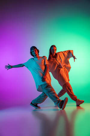 Stylish young hip-hop dancers, emotive girl and boy in action and motion in casual sports youth...