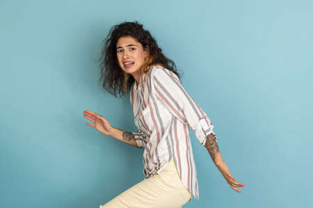 Half-length shot of beautiful girl, fashion female model with tattoo on her hands isolated on light blue studio background. Concept of emotions, feelingsの写真素材