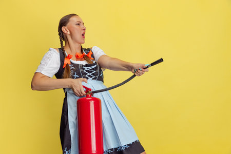Comic portrait of beautiful Oktoberfest woman, waitress wearing a traditional Bavarian or german dirndl isolated on yellow studio background.の写真素材