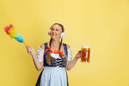 Comic portrait of beautiful Oktoberfest woman, waitress wearing a traditional Bavarian or german dirndl isolated on yellow studio background.の写真素材