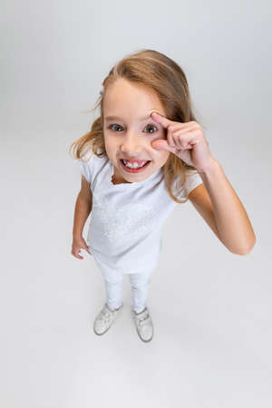 High angle view of beautiful little girl with long hair in modern stylish outfit posing isolated on...