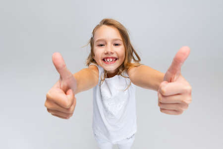 High angle view of beautiful little girl with long hair in modern stylish outfit posing isolated on white studio background. Happy childhood concept.の写真素材