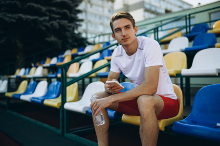 Portrait of young Caucasian man, male athlete, runner isolated at public stadium, sport court or running track outdoors. Summer sport games.の写真素材