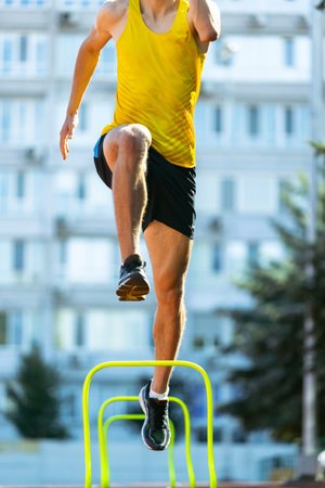 Young Caucasian sportive man, male athlete, runner jumping high at public stadium, sport court or...