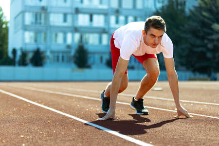 One young sportive man, male athlete, runner practicing alone before race at public stadium, sport court or running track, outdoors. Professional sport games.の写真素材
