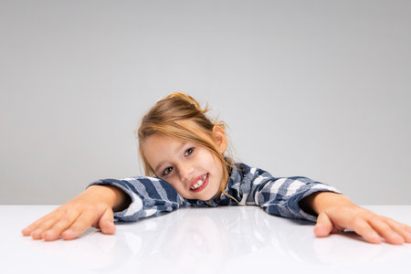 Portrait of beautiful little girl looking at camera, making faces isolated on gray studio background. Human emotions, facial expression concept.の写真素材