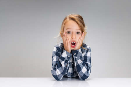 Portrait of beautiful little girl looking suprised, shocked isolated on gray studio background....