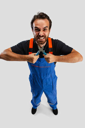 High angle view of young man, male auto mechanic or fitter in dungarees with work tools isolated over white studio background.の写真素材