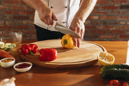 Close-up hands of male chef, cook cutting fresh vegetable salad in his cafe, restaurant kitchen. Concept of a correct, healthy diet.の写真素材