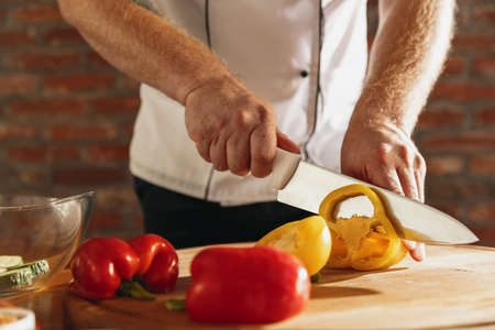 Close-up hands of male chef, cook cutting fresh vegetable salad in his cafe, restaurant kitchen. Concept of a correct, healthy diet.の写真素材