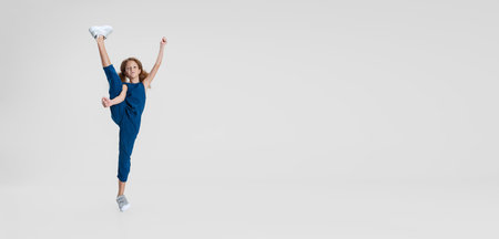 Flyer with little Caucasian cute curly beautiful girl in blue stylish jumpsuit stands in a twine isolated over white studio background. Leisure activity conceptの写真素材