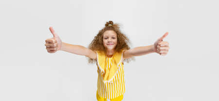 One little cute curly preschool beautiful girl looking at camera isolated over white studio background.の写真素材