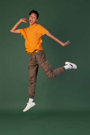 Portrait of young man, student in casual clothes jumping isolated on green vintage studio backgroud. Human emotions concept.の写真素材