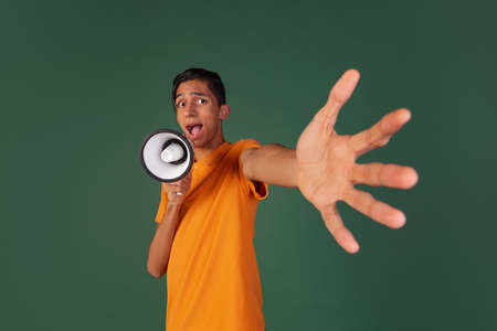 Close-up young man, student in casual clothes with magephone isolated on green vintage studio backgroud. Human emotions concept.の写真素材
